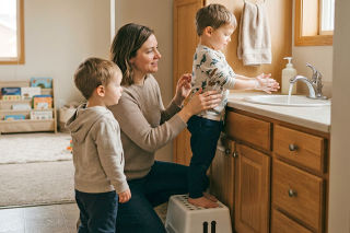 A young child washing their hands at a sink.